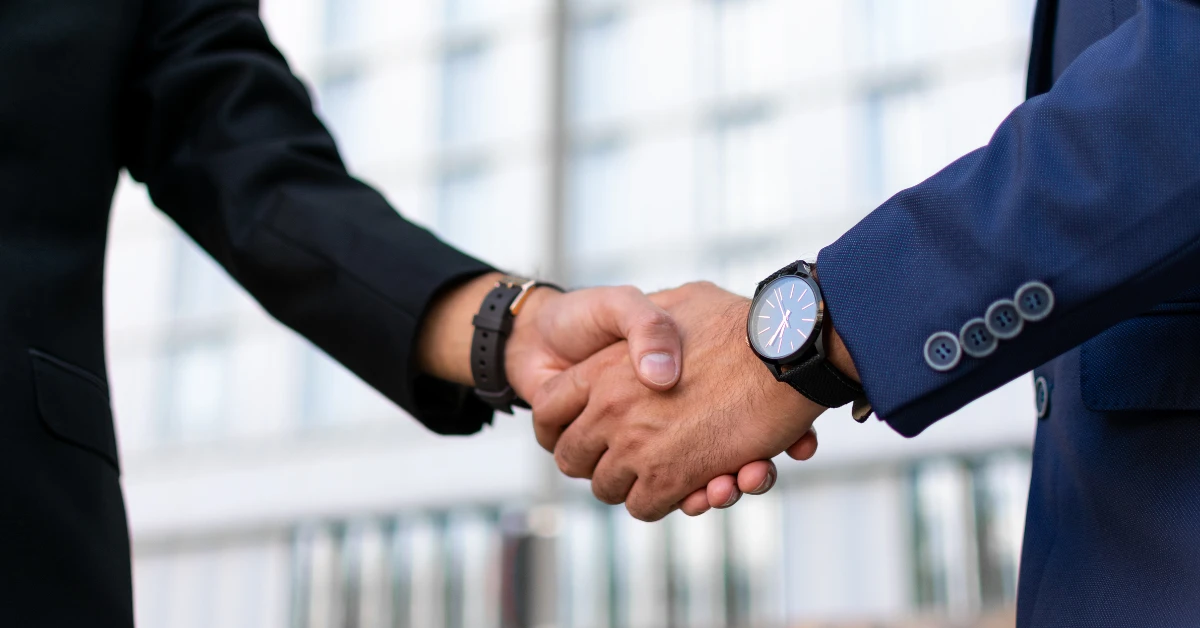 Dos personas estrechando manos tras firmar acuerdo